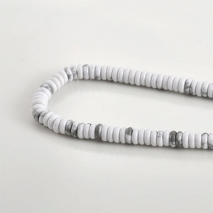 Detailed macro view of white Howlite heishi beads with natural grey marble textures