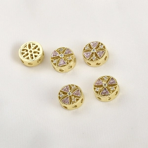 Macro detail of 14k gold-plated spacer beads with pink and white cubic zirconia accents