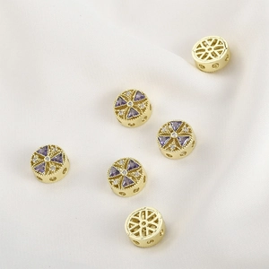 Macro shot of 14k gold-plated round beads with purple cubic zirconia and hollow geometry