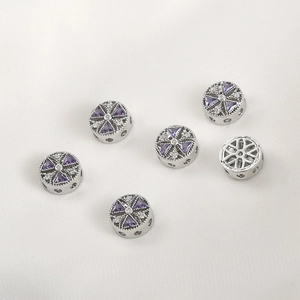 Detailed view of silver circular DIY beads with purple cubic zirconia and side holes
