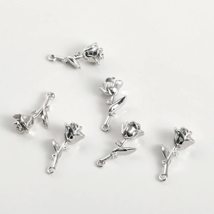 Macro shot of silver rose pendants with inlaid zircons and loops for jewelry making