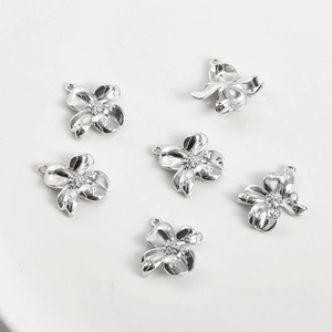 Macro shot of silver five-petal flower charms with zircon inlay for jewelry making