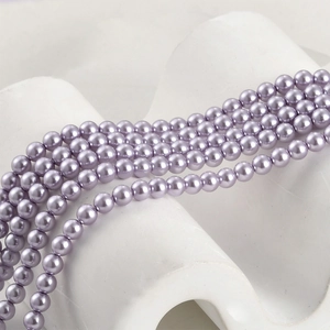 Macro detail of glossy grape purple glass pearls arranged on a white ceramic display