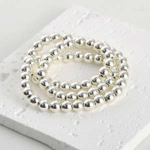 Macro view of polished silver hematite round beads on white stone background