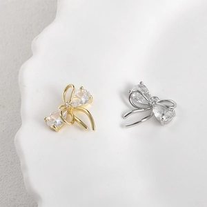 Macro detail of 14k gold-plated bow charm with sparkling cubic zirconia inlay for jewelry