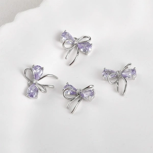 Detail of four silver bow charms with purple pear-shaped zirconia for DIY jewelry