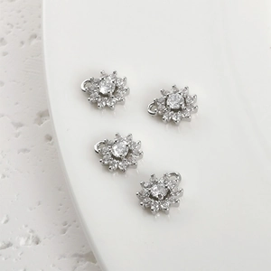Macro shot of silver four-leaf flower pendants with zircon stones for DIY jewelry making