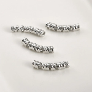 Macro shot of four silver-plated curved spacer tubes with textured spiral surface for DIY jewelry