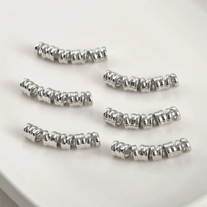 Detailed view of six silver-colored spiral metal tube beads for jewelry making