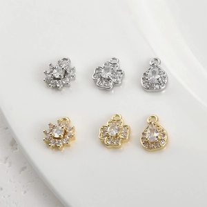 Macro detail of 14k gold plated clover and teardrop pendants with sparkling zircon stones