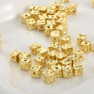 Close-up of 14k gold-plated square beads with hammered texture for DIY jewelry making