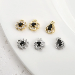 Macro shot of 14k gold clover and teardrop pendants with black stones for DIY jewelry