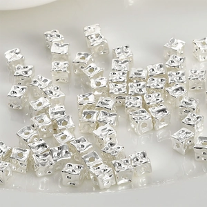 Close-up of silver square beads with hammered texture for DIY jewelry making