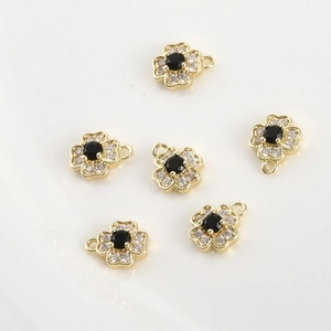 Macro view of 14k gold flower charms with black stone centers and zircon petals