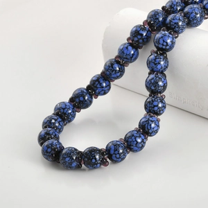 Macro view of handmade glass blueberry beads with deep blue and black speckled patterns