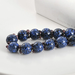 Macro detail of handmade glass blueberry beads for DIY jewelry with glossy blue texture