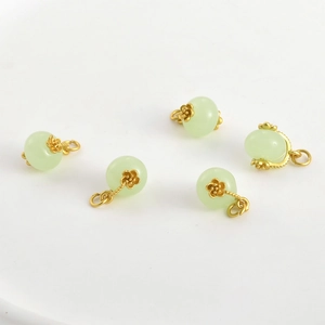 Dettaglio dei fermagli a petalo in oro 18k e dei ciondoli rotondi in giada verde pallido