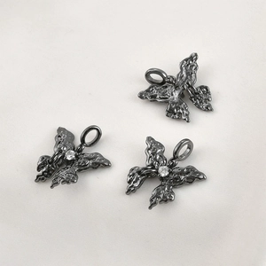 Detailed macro of three gunmetal butterfly charms with lava texture and zircon center