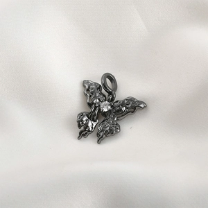Macro detail of dark butterfly pendant with crystal inlay on white satin background