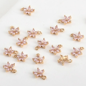 Détail de breloques fleurs à cinq pétales dorées avec zircons roses pour bijoux DIY