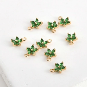 Détail de pendentifs fleurs à cinq pétales dorés sertis de zircons verts brillants