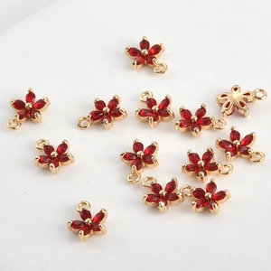Détail macro de pendentifs fleurs à cinq pétales dorés avec zircon rouge pour bijoux DIY