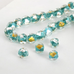 Macro shot of peacock blue handmade glass beads with embedded gold leaf for jewelry making