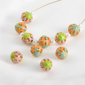 Vista macro de cuentas de flores esmaltadas en oro de 18K con pedrería de colores