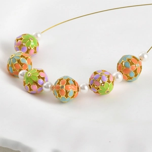 Detalle macro de cuentas de flores de esmalte bañadas en oro 18K y perlas para joyería