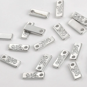 Vue macro de breloques rectangulaires en argent avec motifs papillon pour bijoux DIY