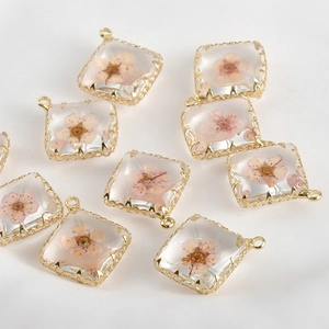 Makroaufnahme quadratischer 14k vergoldeter Harzanhänger mit echten rosa Trockenblumen