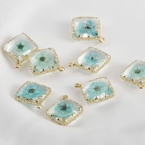 Makroaufnahme quadratischer 14k vergoldeter Anhänger mit blauen Trockenblumen für DIY