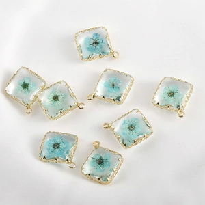 Detailaufnahme quadratischer 14k vergoldeter Anhänger mit blauen Trockenblumen in Harz