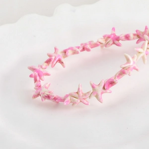 Detailed close-up of pink and white synthetic starfish beads on a white ceramic plate