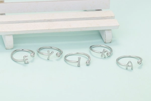 Anillo ajustable de plata con letra inicial y circonita en un banco de madera
