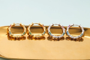 Detail of gold and silver bamboo hoop earrings with colorful inlaid zircon gemstones