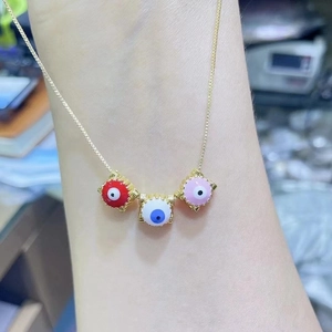 Bohemian evil eye pendant necklace with red white and pink charms on a gold chain