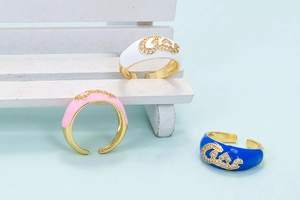 Macro detail of colorful enamel rings with zircon Arabic script on light blue surface