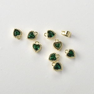 Macro view of 14k gold-plated heart pendants with faceted green zircon and detailed metal edges