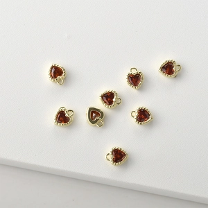 Macro view of 14k gold-plated heart charms with red cubic zirconia for DIY jewelry making