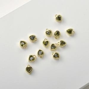 Macro view of heart-shaped olive green zircon charms with 14k gold plated beaded frames