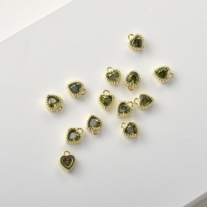 Macro view of 14k gold-plated heart charms with emerald green cubic zirconia stones
