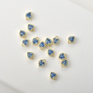 Macro view of 14k gold-plated heart charms with blue zircon and delicate wavy edges