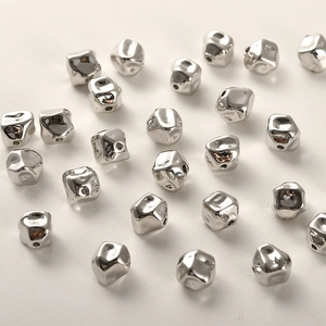 Makro-Detail von unregelmäßigen versilberten Distanzperlen mit glänzender Metallstruktur