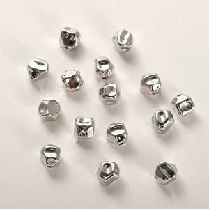 Detailaufnahme unregelmäßiger versilberter Perlen mit Metallstruktur für DIY-Schmuck