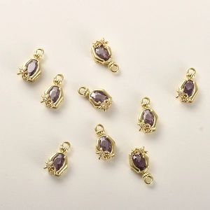Makro-Detail von 14k vergoldeten Schmetterlingsanhängern mit lila Zirkonia und kleinen Blumenmotiven