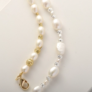 Dettaglio macro di perline sfaccettate placcate in oro 14k e perle su una collana