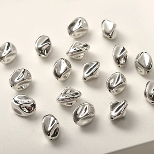 Detalle macro de cuentas espaciadoras de metal plateado irregular para creación de joyas