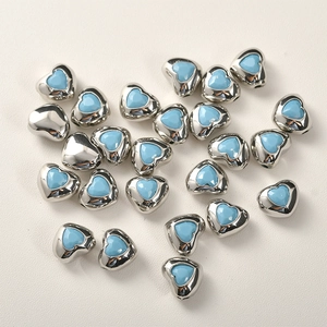 Dettaglio macro di perline a cuore argento con centri blu per la creazione di gioielli