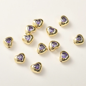 Dettaglio macro di perline in zircone a forma di cuore placcate oro 14k per gioielli fai da te